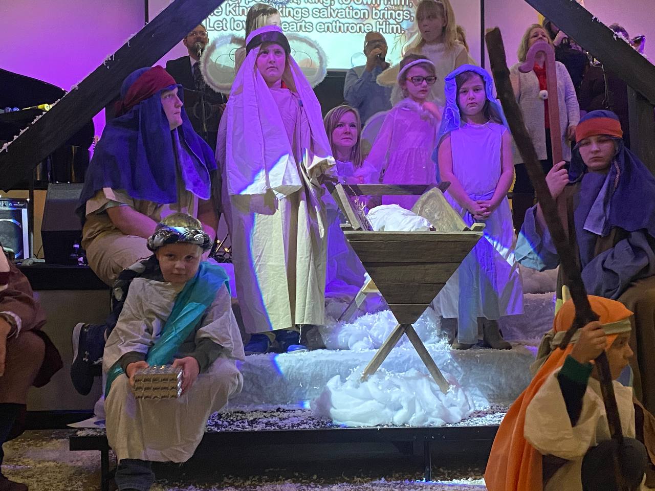 several kids are gathered in a manger scene