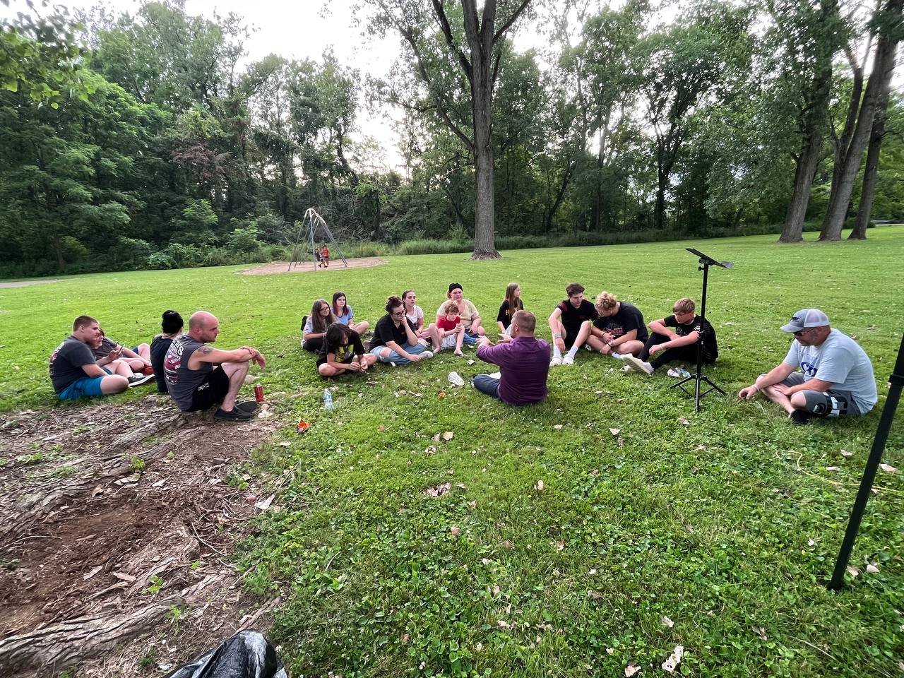 Zion's Refuge Church youth are gathered outside for a bible study on a lawn